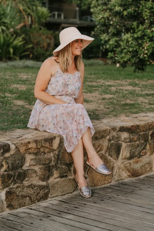 wearing-champagne-glitter-avarca-sandals-on-stone-wall
